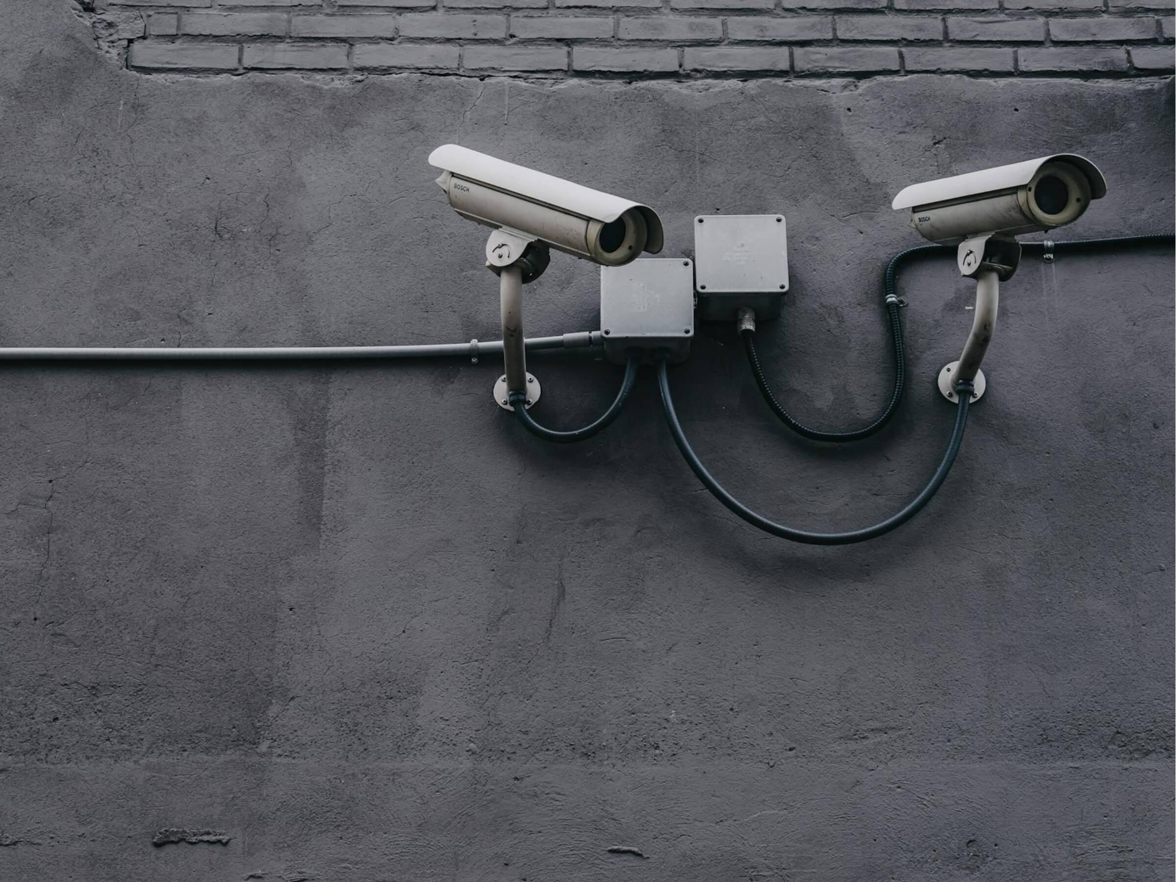 two security cameras on a grey wall