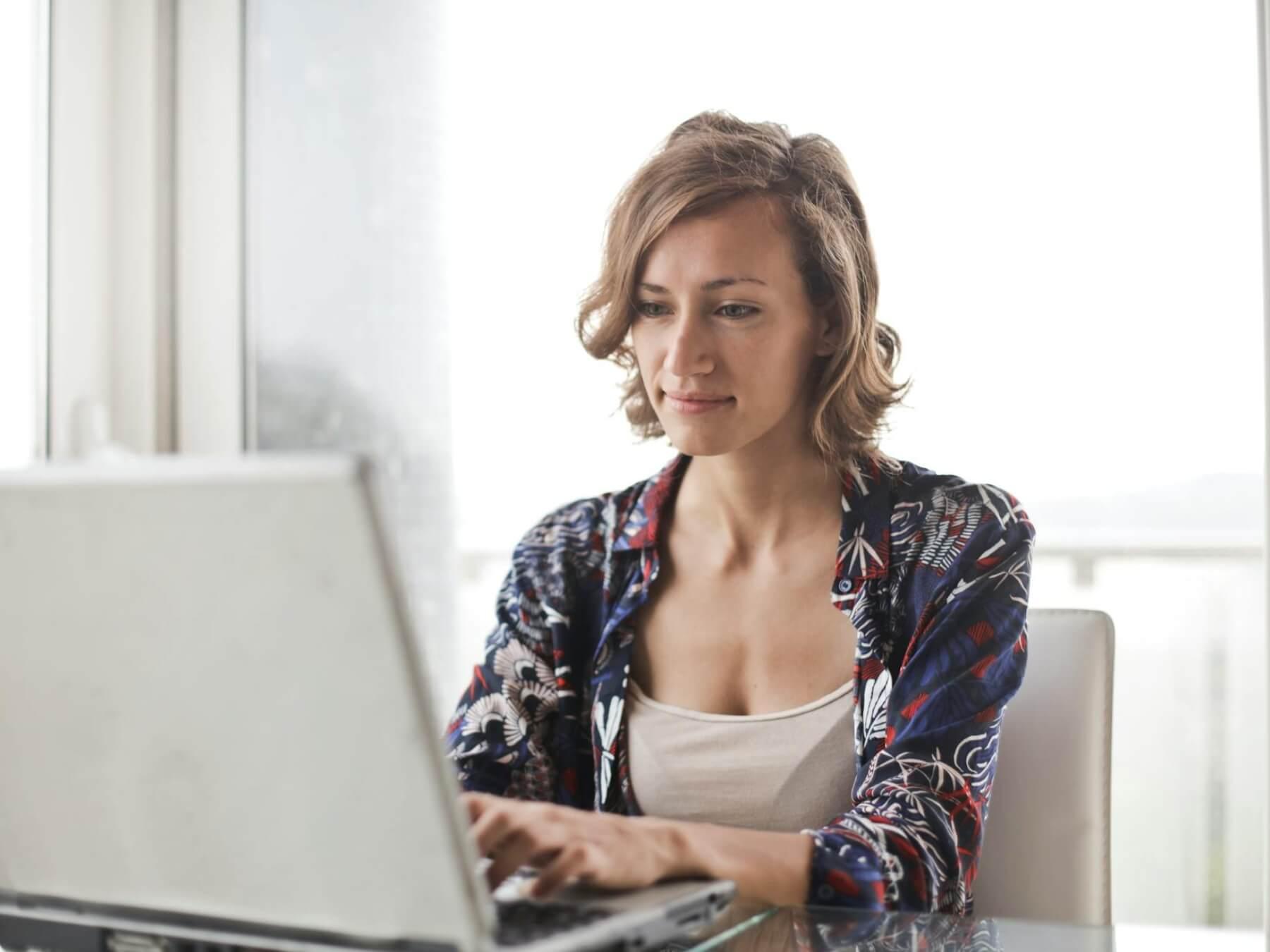 A woman in a floral top using a laptop.