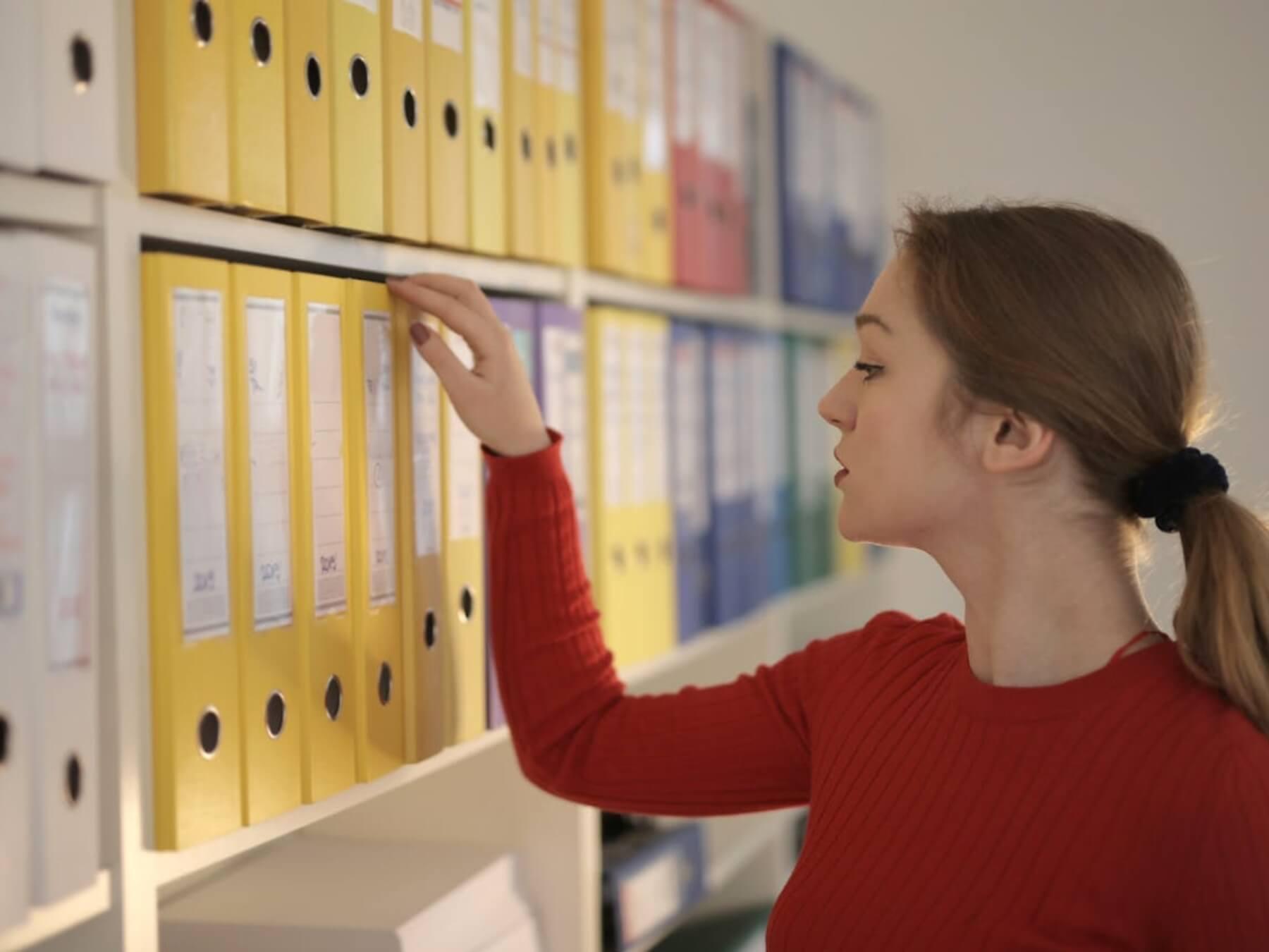 A woman looking at files in a cupboard.