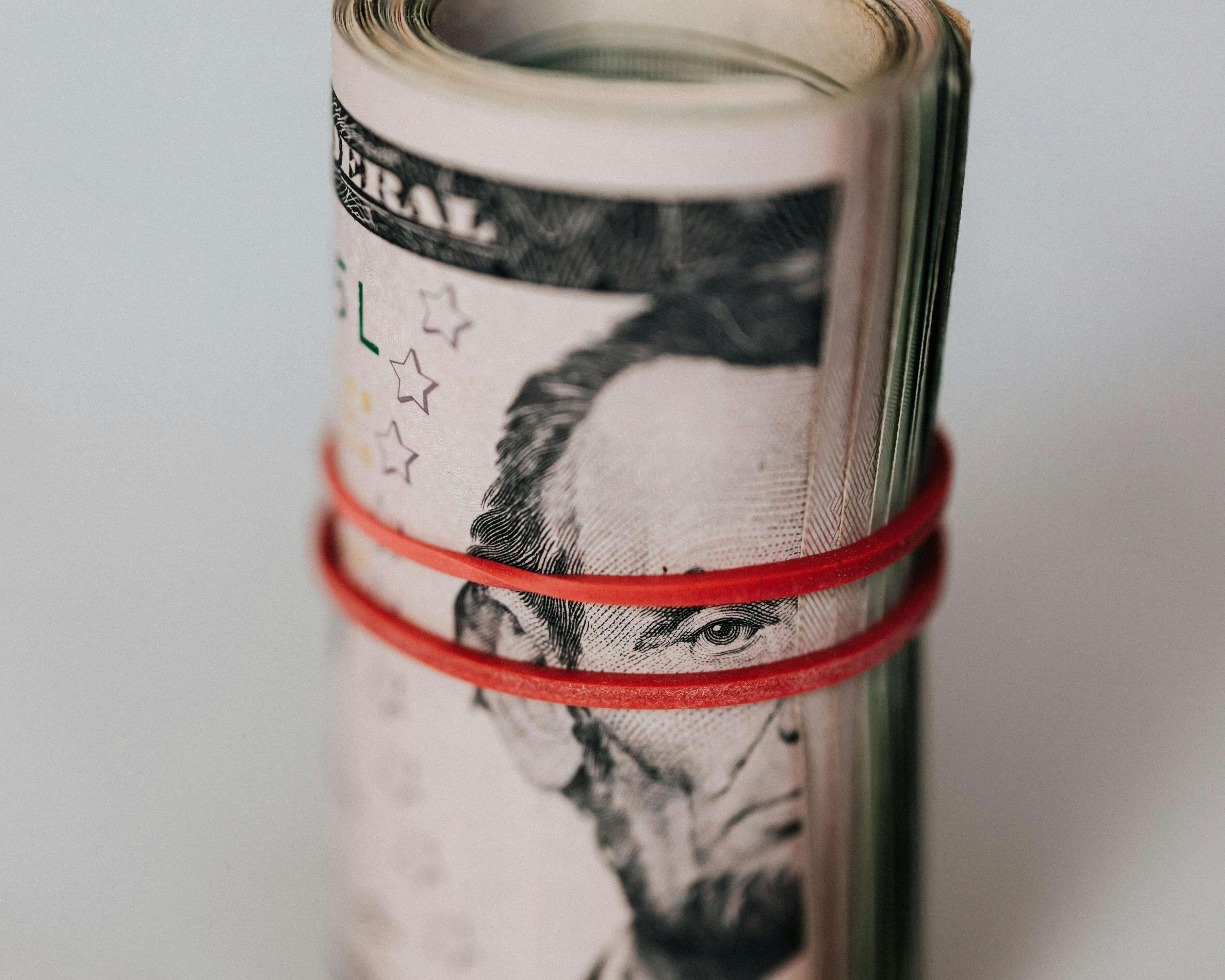 Roll of American dollars tightened with red band.